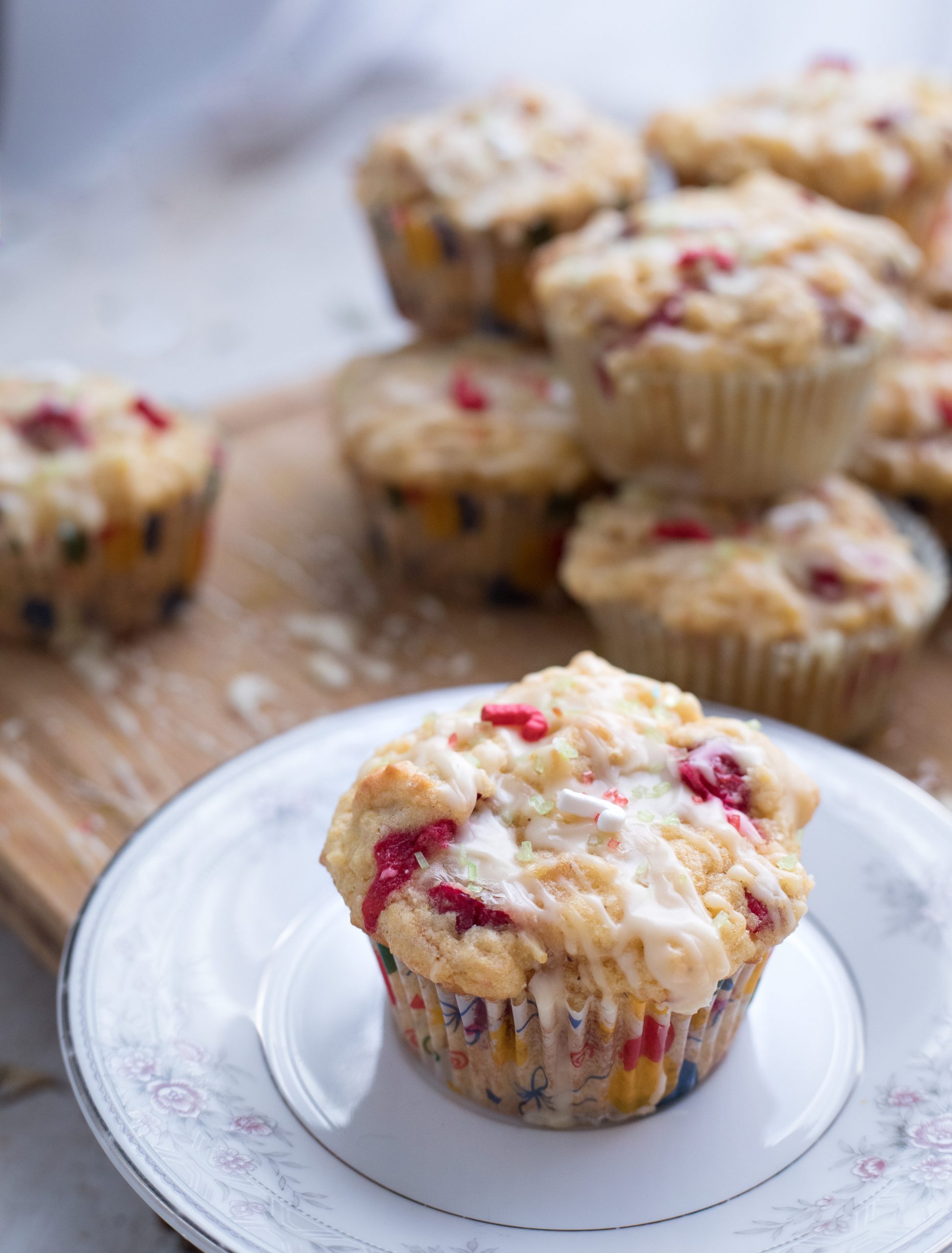 A cranberry orange muffin on a plate, with more muffins in the background