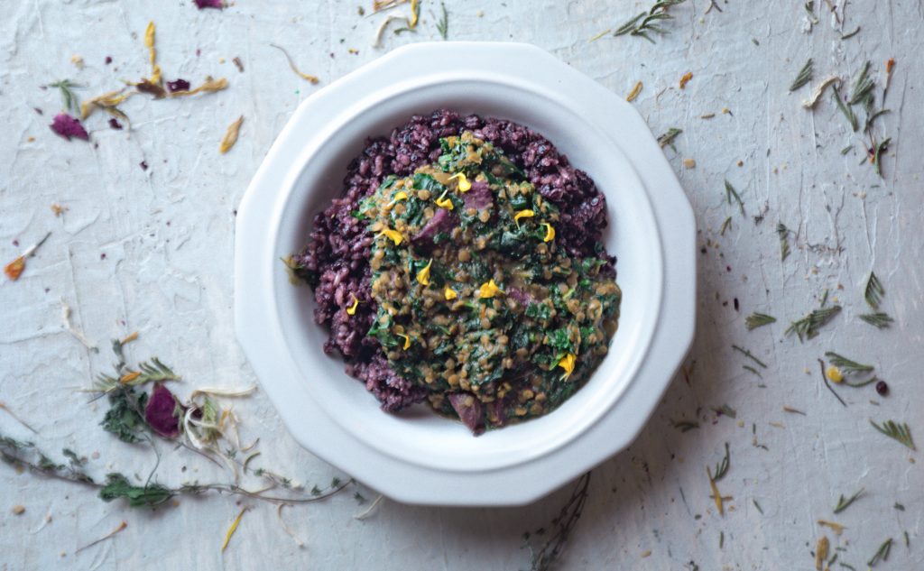 Purple Potato and Spinach Dal in a bowl on a white table.