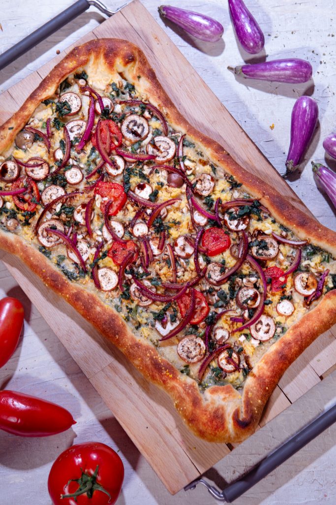 A vegetable pizza on a wooden cutting board