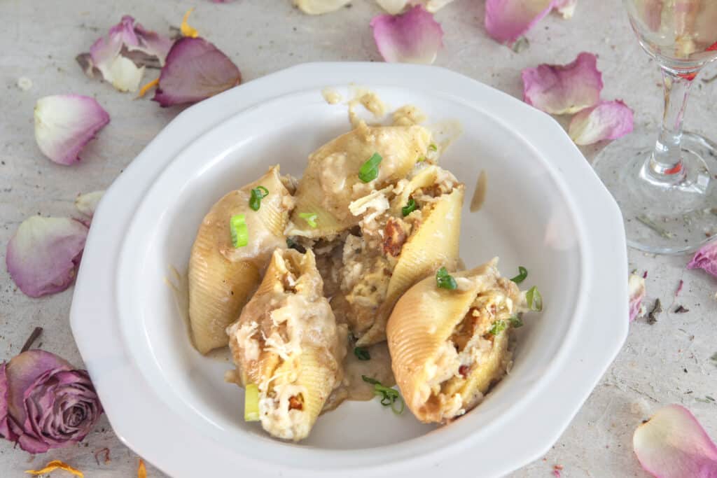 Stuffed large pasta shells with green onion on a white plate