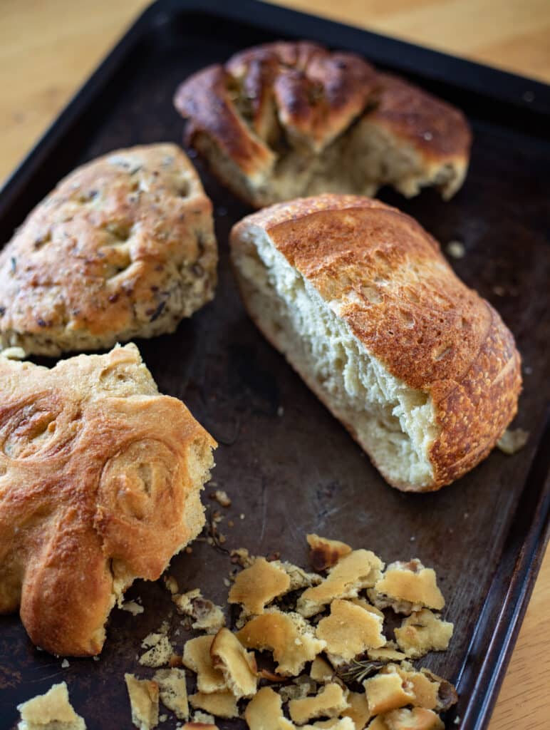 Four different half loaves of bread on a baking sheet