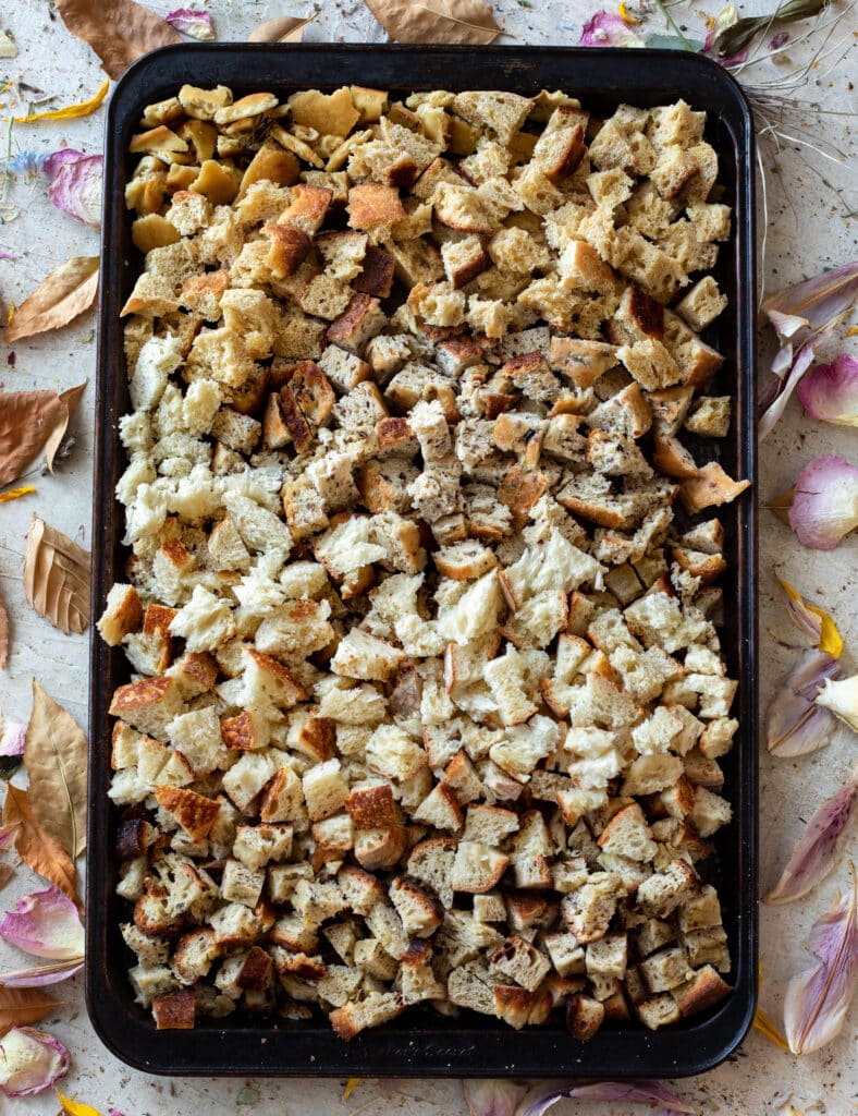 Multiple kinds of breadcrumbs and bread cubes on a baking sheet