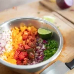 a bowl of chopped onions, tomatoes, and peppers in colors ranging from white, yellow, purple, and green