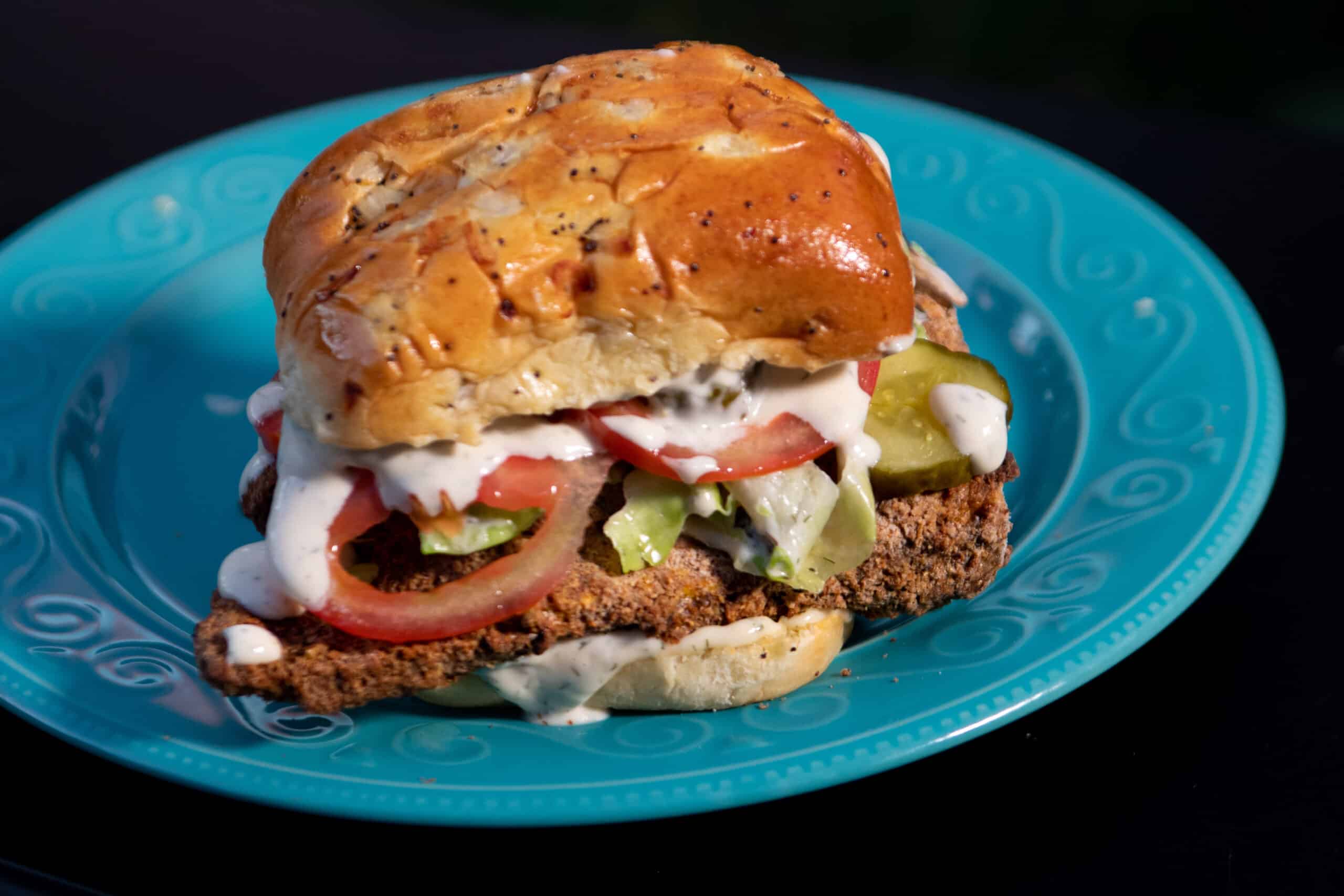 Fried Chicken of the Woods Sandwich, dripping in ranch, with tomatoes and pickles on an onion bun
