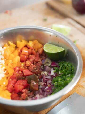 a bowl of salsa on a cutting board