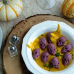 a bowl of purple skull shaped gnocchi in a pumpkin sauce