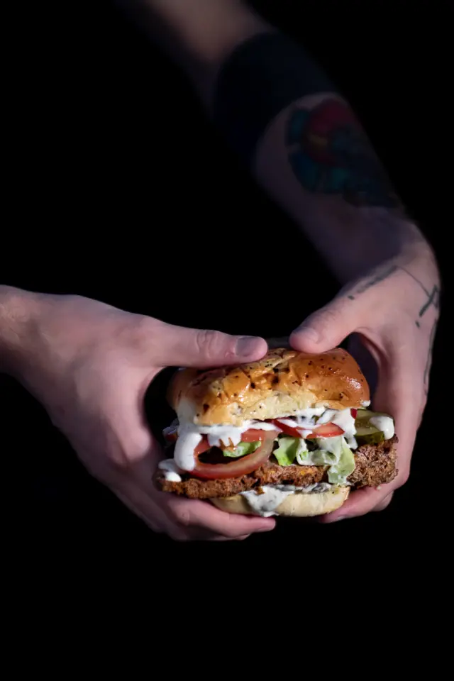 Holding a fried chicken of the woods sandwich with ranch dripping down