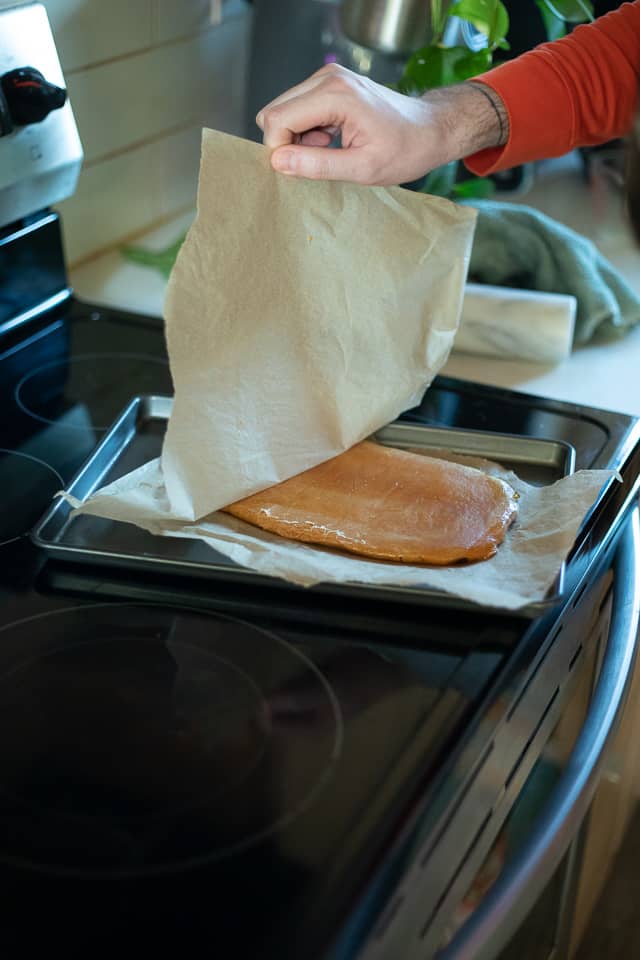 lifting parchment paper off the flattened peanut butter caramel
