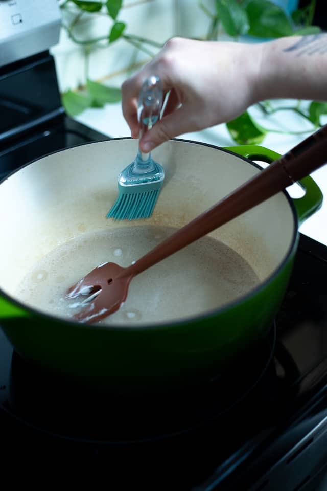 A pastry brush removing sugar off the sides of a pot