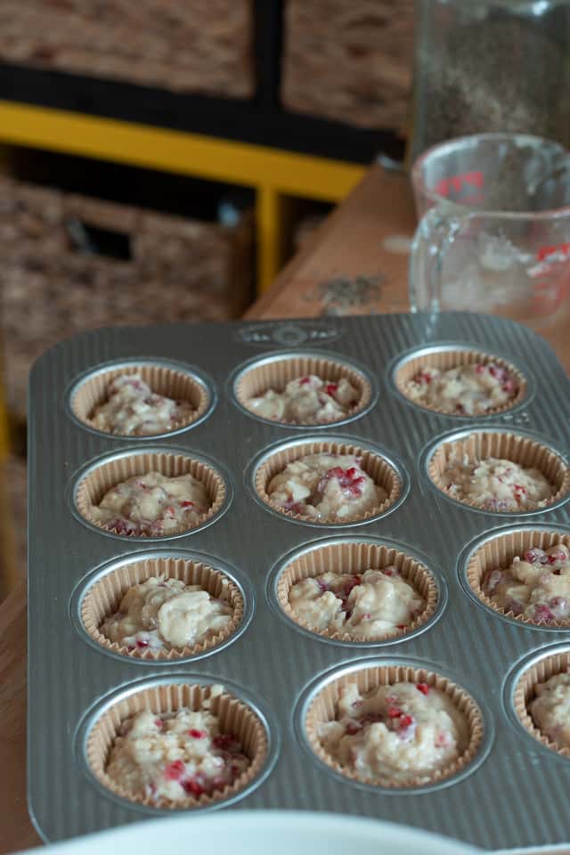 muffin batter inside of muffin tins in a baking sheet on a table