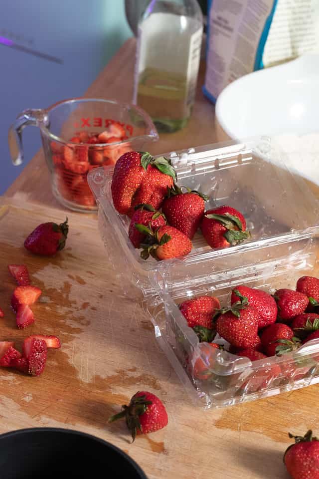 Fresh strawberries being cut up into a measuring cup