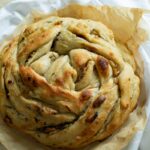 a loaf of pull apart sourdough bread on parchment paper