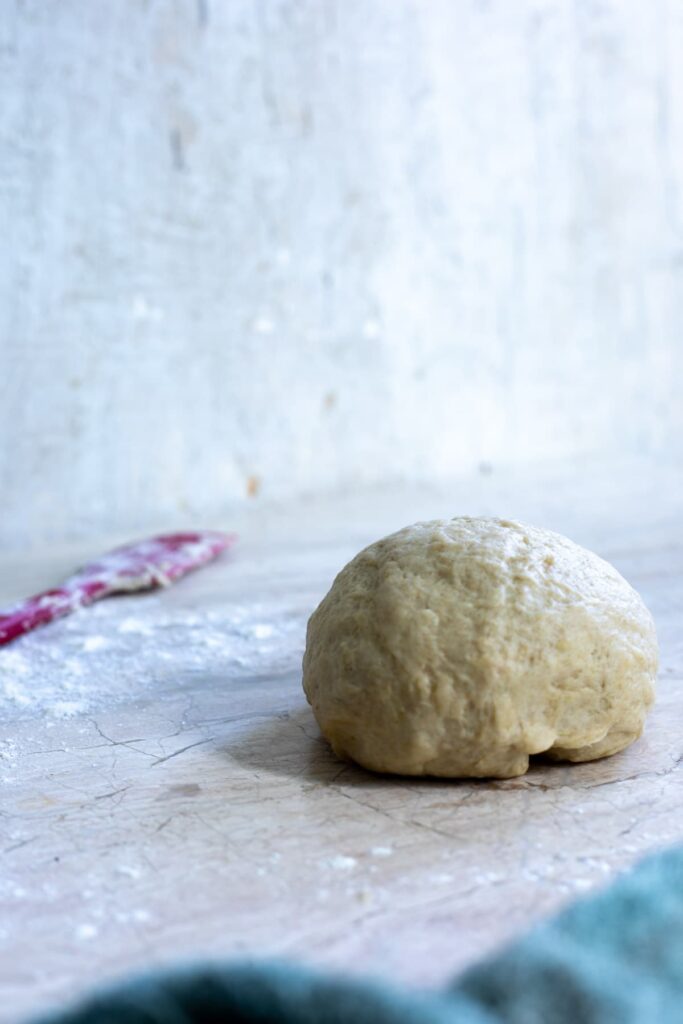 a ball of sourdough tortilla dough on a marble counter