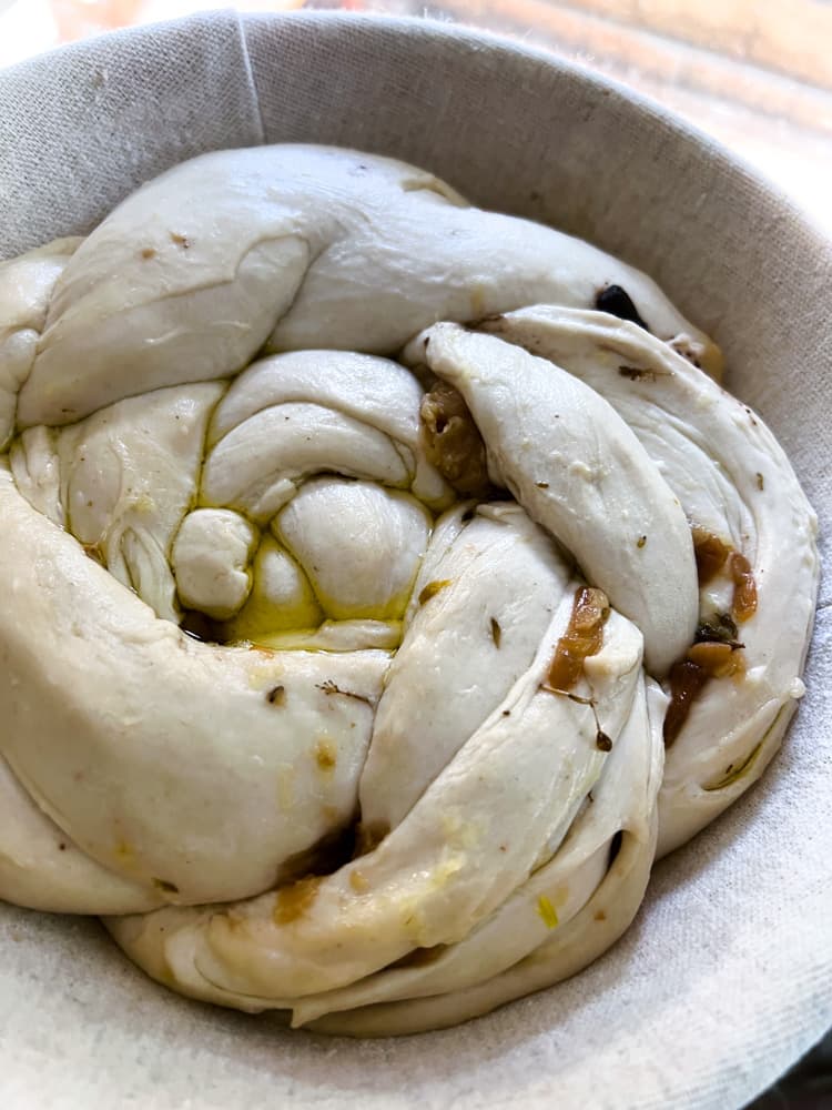 Braided dough in a circle loaf with bits of garlic peeking out through the edges