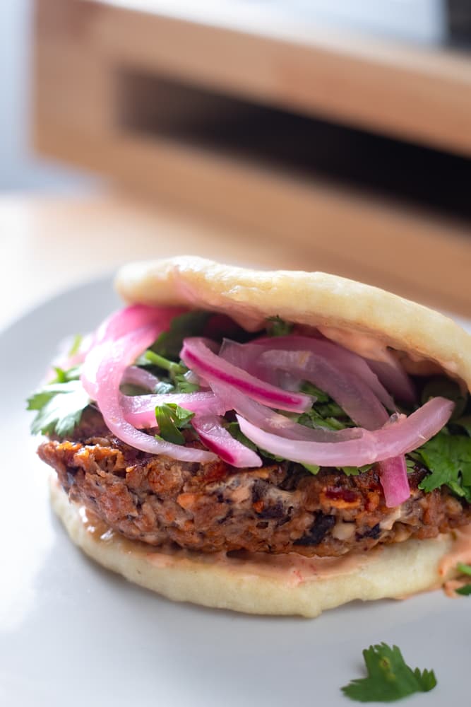 a burger inside of a bao bun on a table