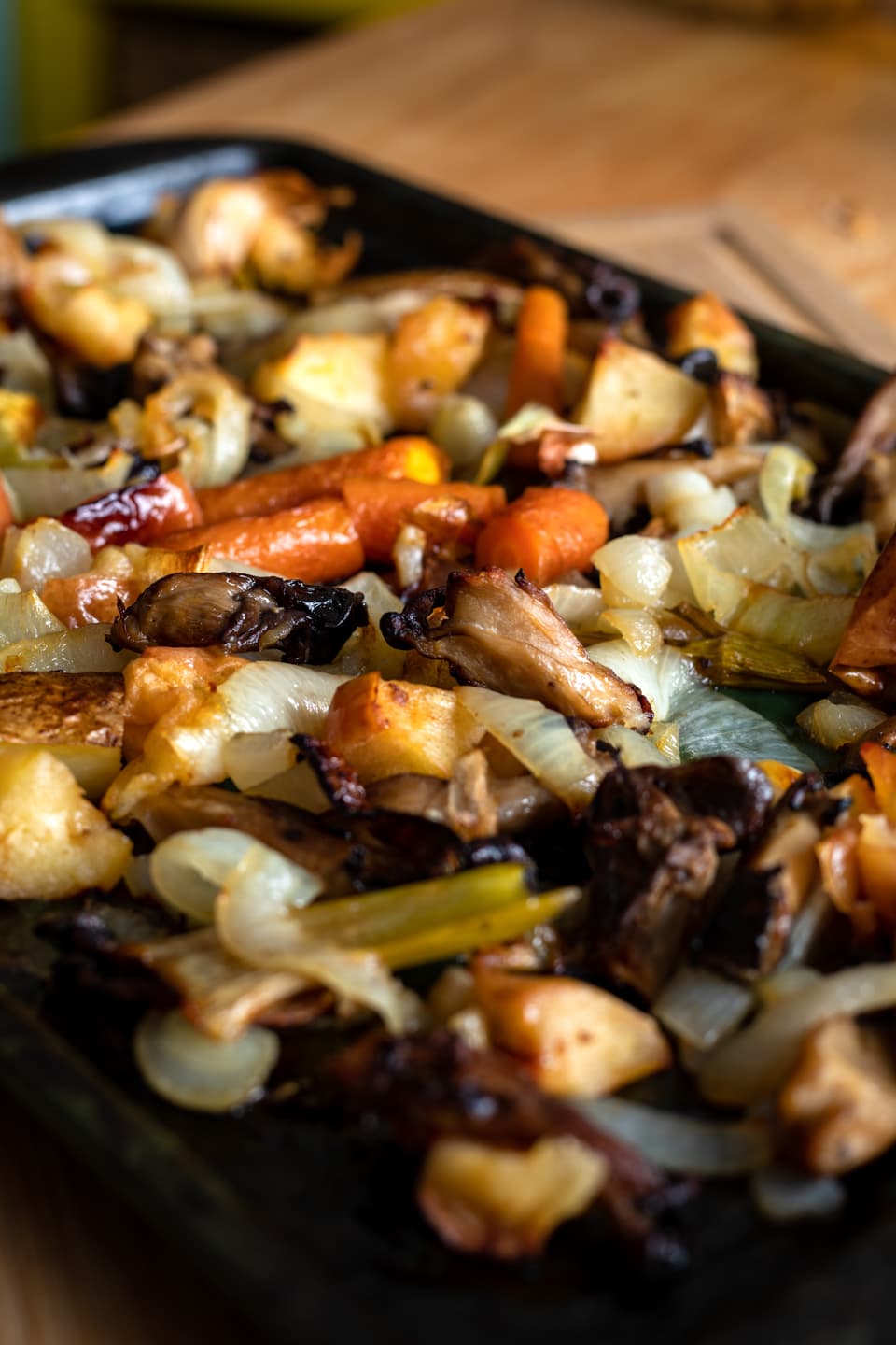 A baking sheet filled with roasted vegetables, mushrooms, and apples