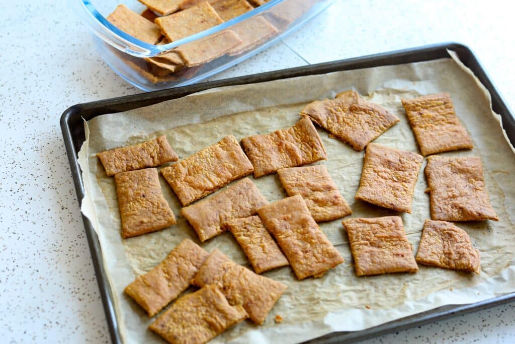 crackers on a parchment paper lined metal baking sheet on a countertop