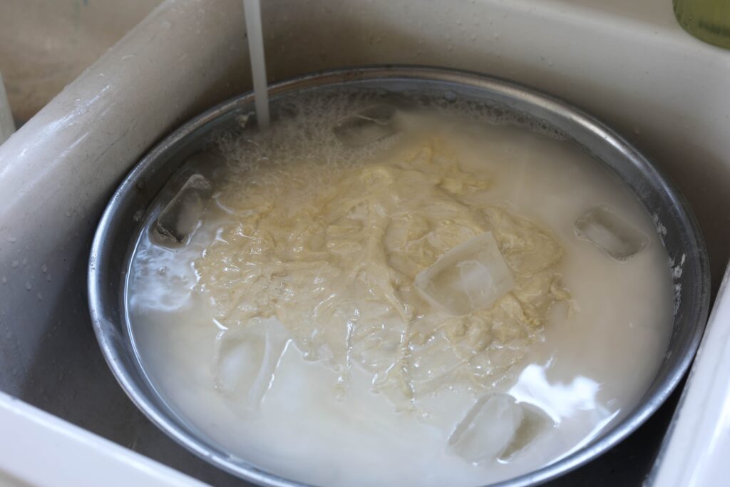 dough in ice water with more cold water being poured in