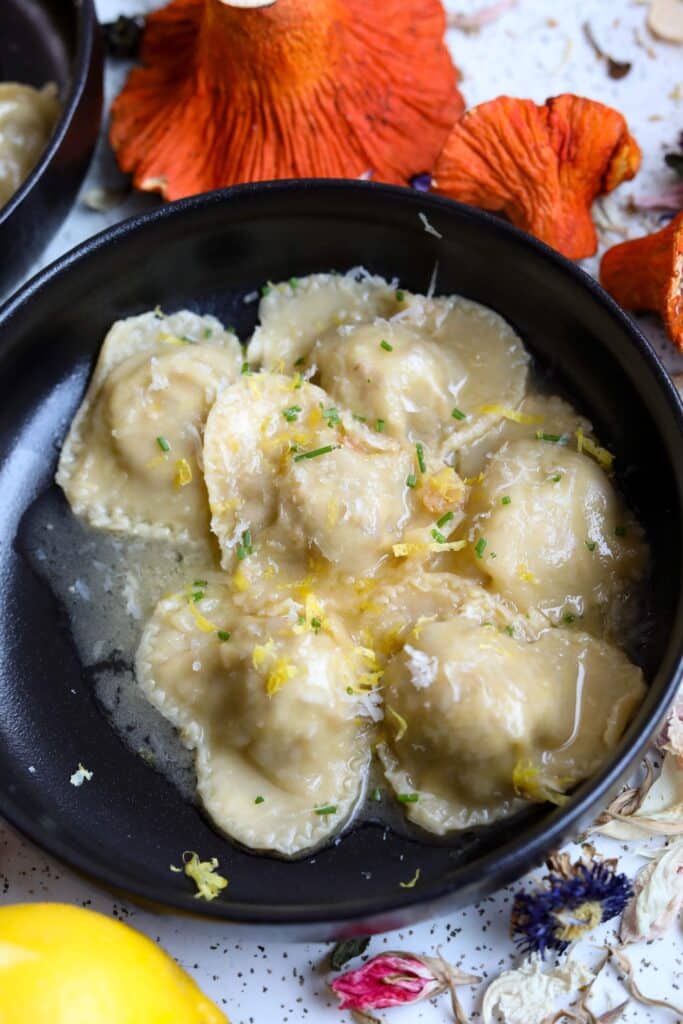 a bowel of pasta next to a lobster mushroom and a lemon