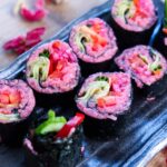 a black square plate of pink sushi