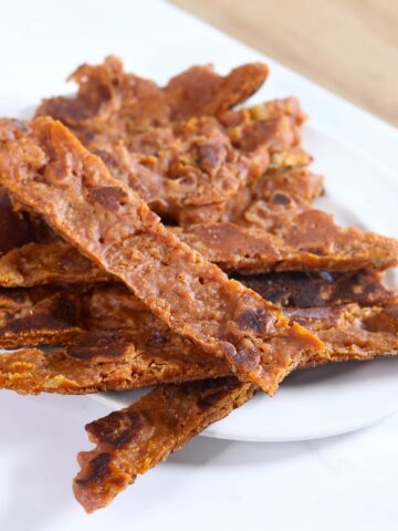 a white plate with strips of vegan jerky stacked in a pile