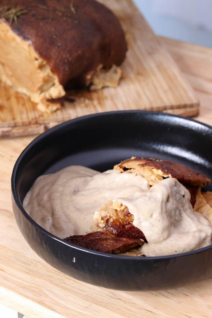 seitan covered in gravy in a black bowl on a wooden table