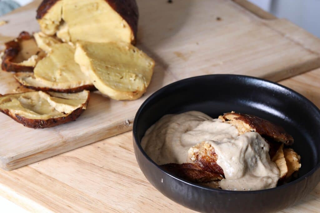 A black bowl filled with seitan that's covered in gravy