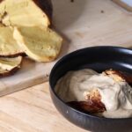 A black bowl filled with seitan that's covered in gravy