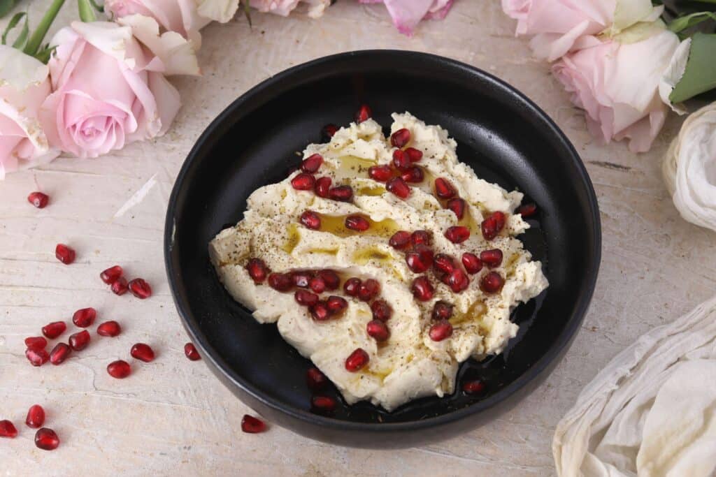 a bowl of labneh with pomegranate, olive oil, and zatar