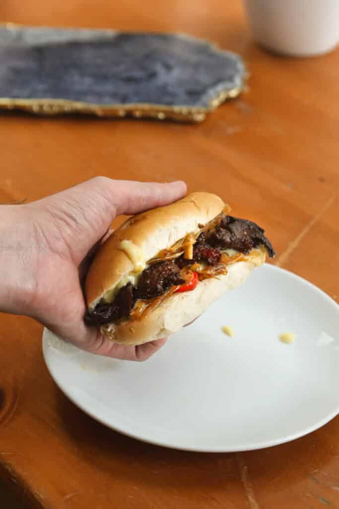 a person holding a sandwich over a white plate