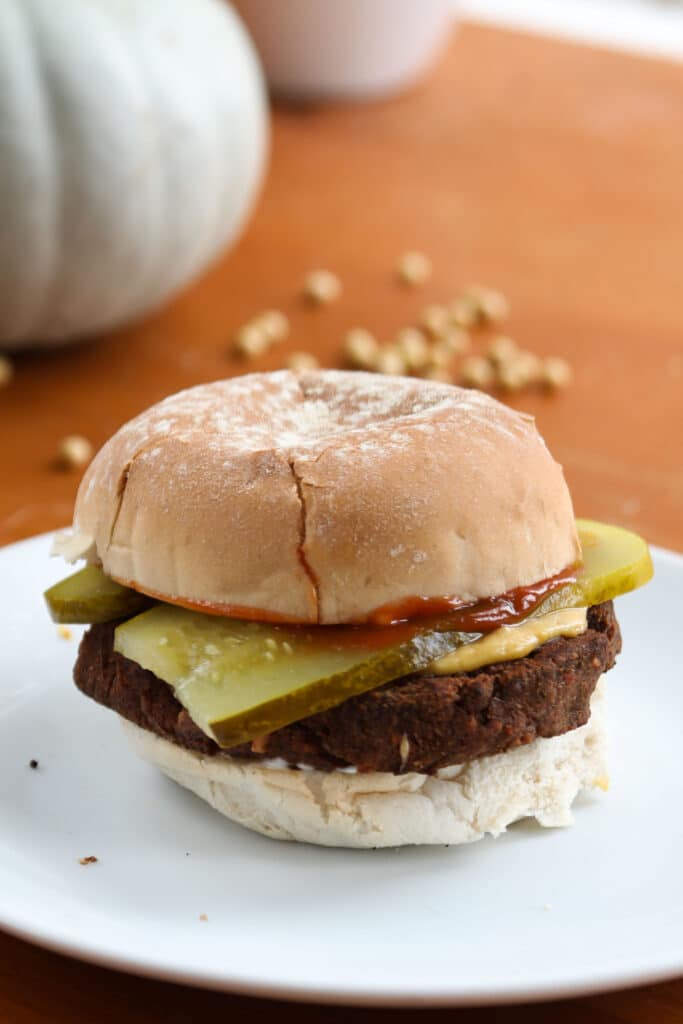 a veggie burger in a bun with pickles, red ketchup, and melty cheese